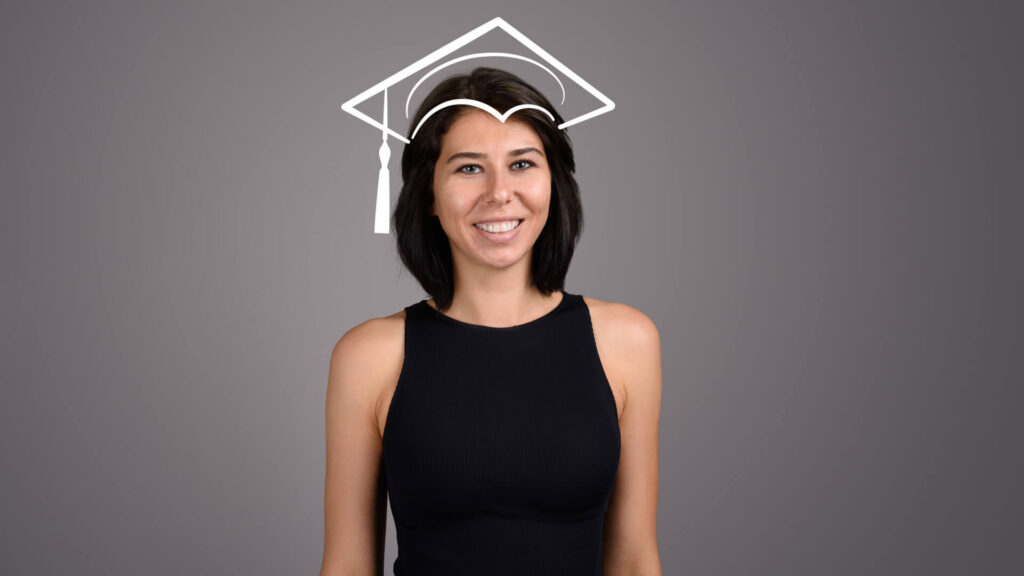 Adult female smiling with an illustration of a graduation cap on her head.