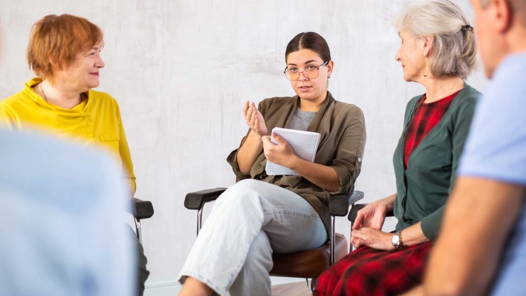 A woman with glasses talks in a group discussion