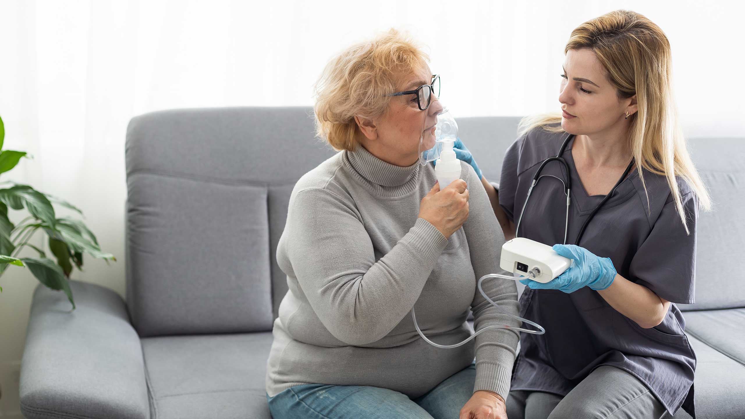 A respiratory therapy student helping an elderly lady with an oxygen mask