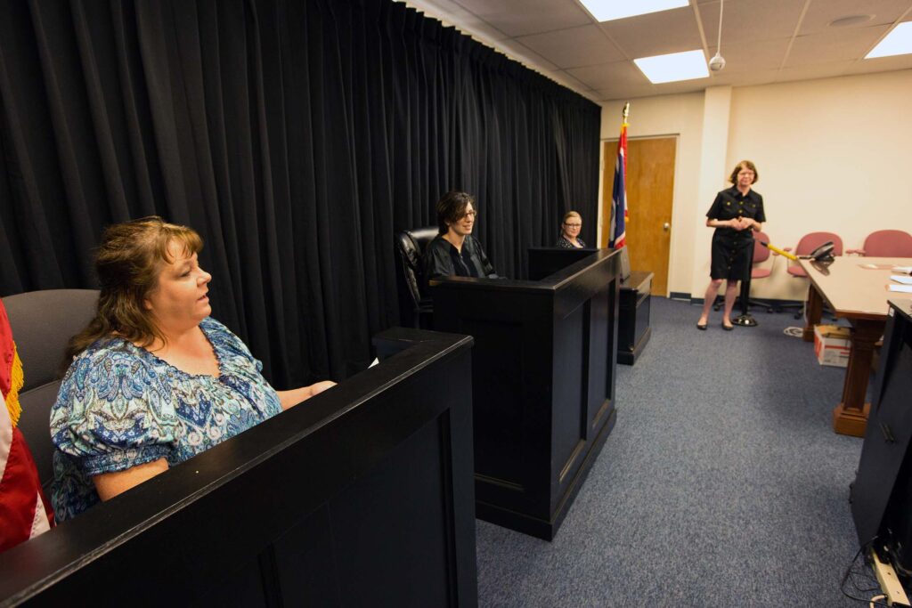 Students observe and participate in a mock courtroom while an instructor leads a criminal justice class.