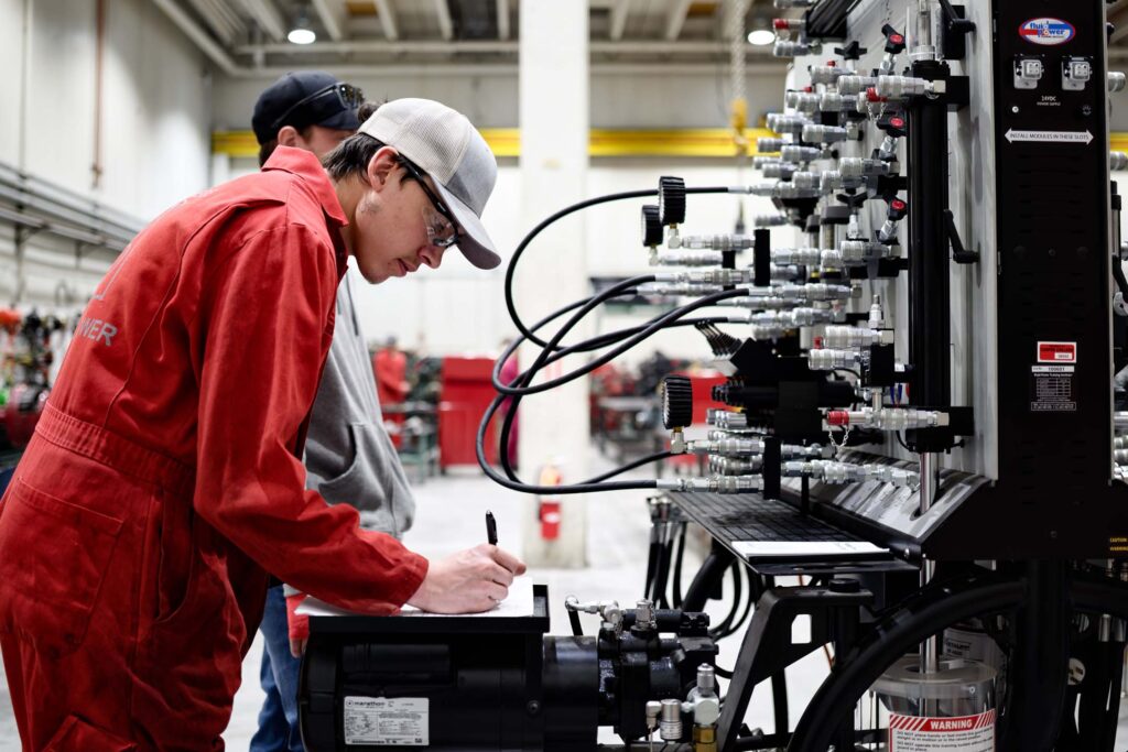 A Diesel Technology student records measurements while working with a hydraulic systems training station in a hands-on lab.