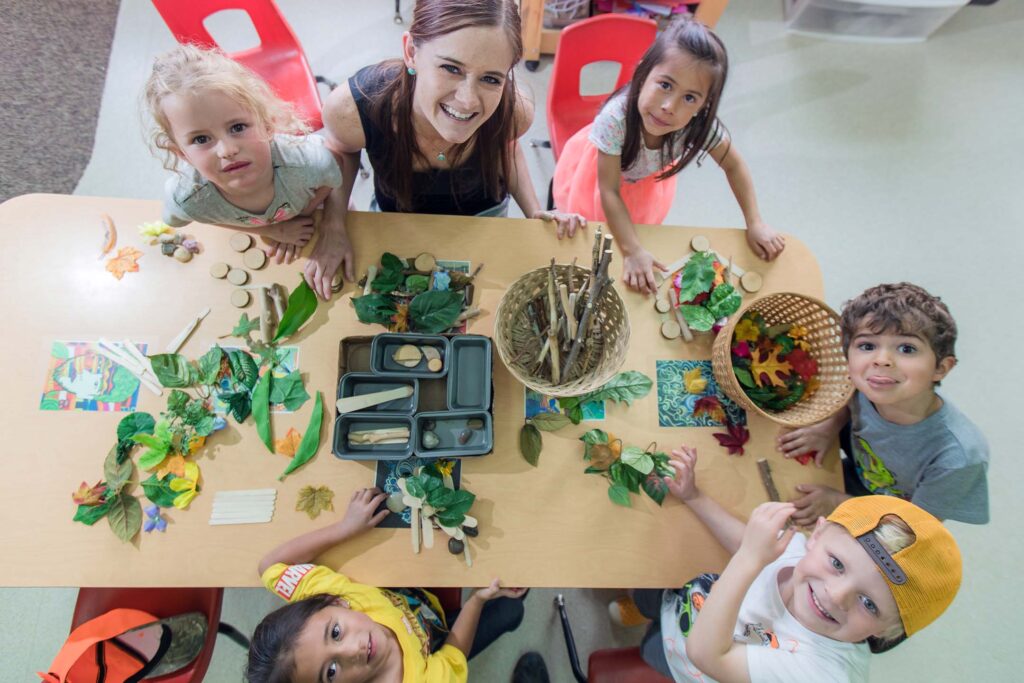 Early childhood education students and children explore nature materials during a collaborative classroom activity.