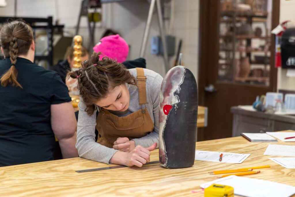 A museum studies student closely examines an artifact during a hands-on collections lab.