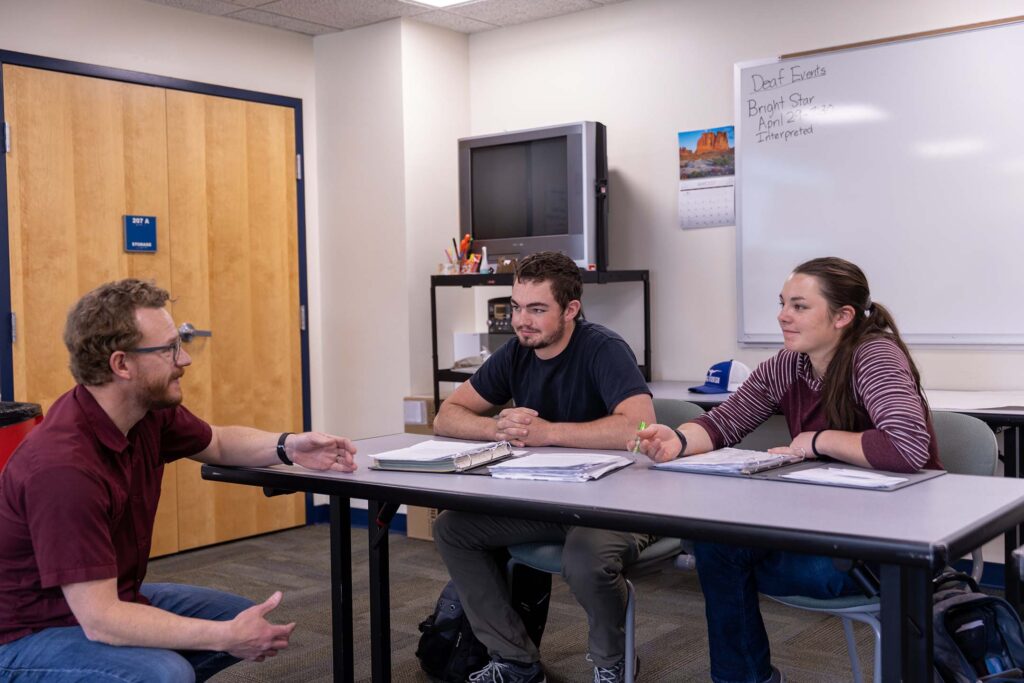 A Spanish instructor engages with two students during a small-group language lesson.
