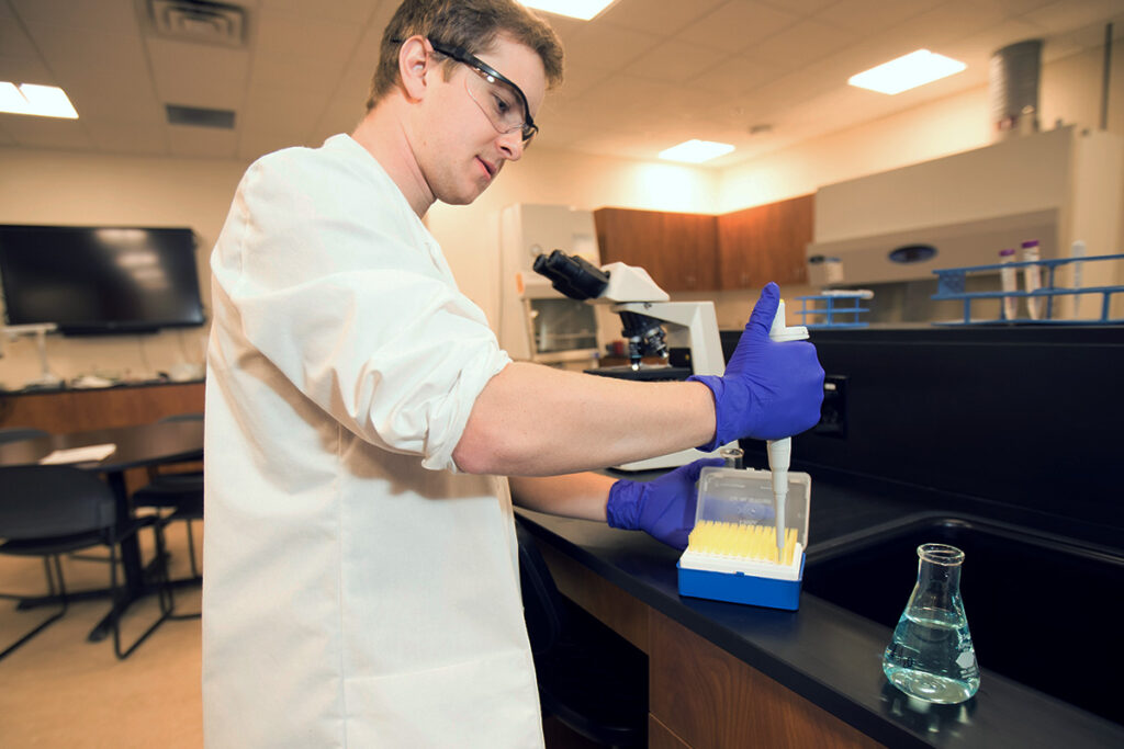 Medical laboratory technology student uses a micropipette to transfer liquid samples in a laboratory.