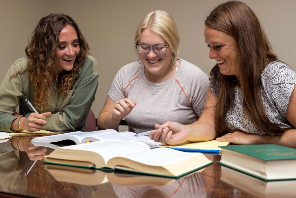 three women studying paralegal studies at a table.