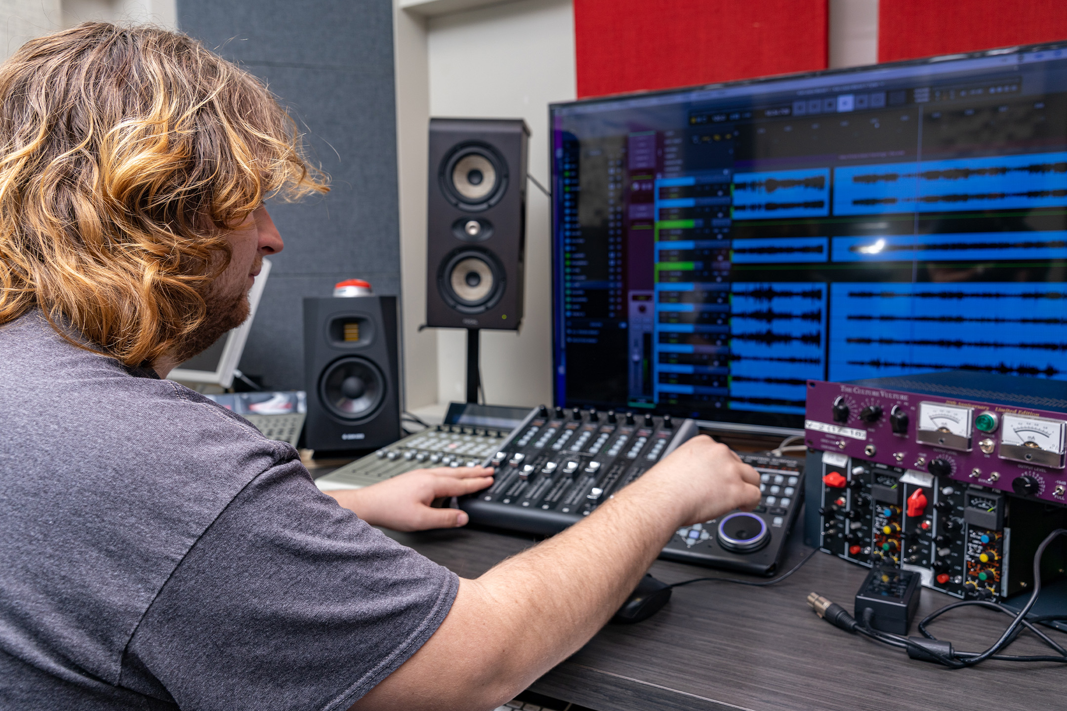 Student working at a sound board for sound recording