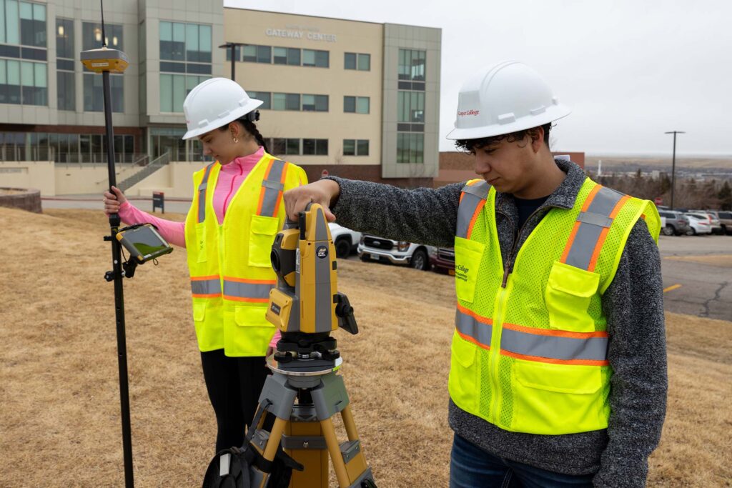 Students surveying with construction staking tools