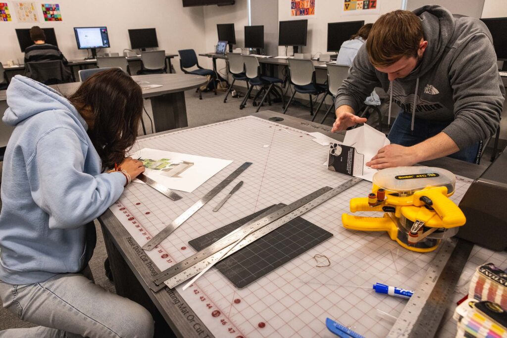 Students cutting out projects for graphic design