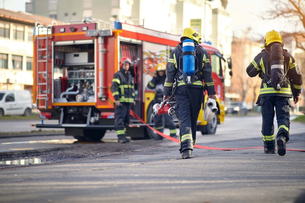 Firefighters walking near a fire truck on a city street. Fire Science