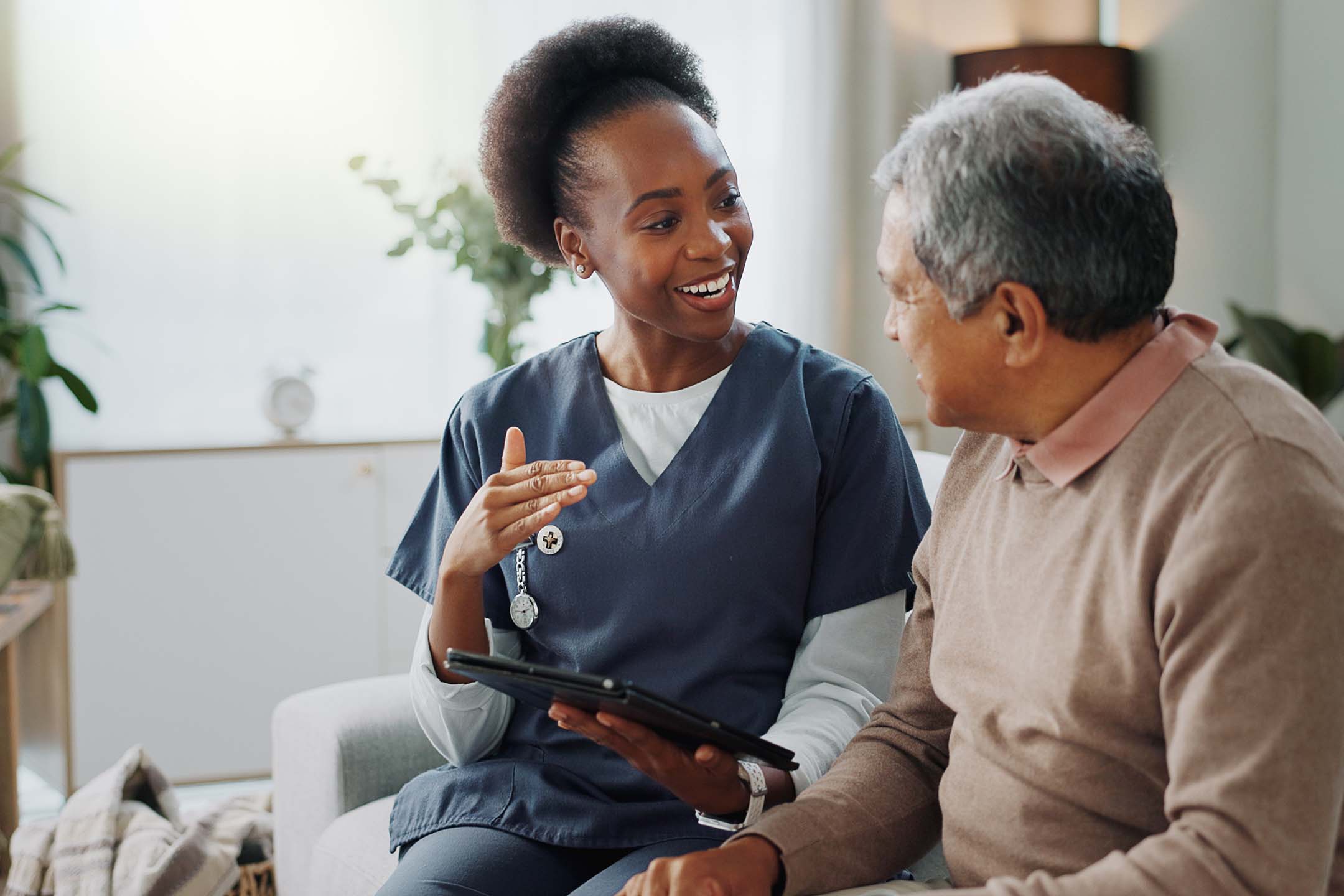 Healthcare worker talking with an older adult during a seated consultation. interprofessional health care