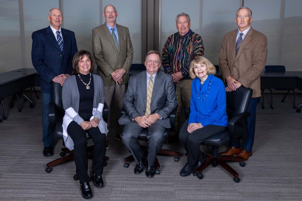 Eight adults in professional attire posed together in a conference room.