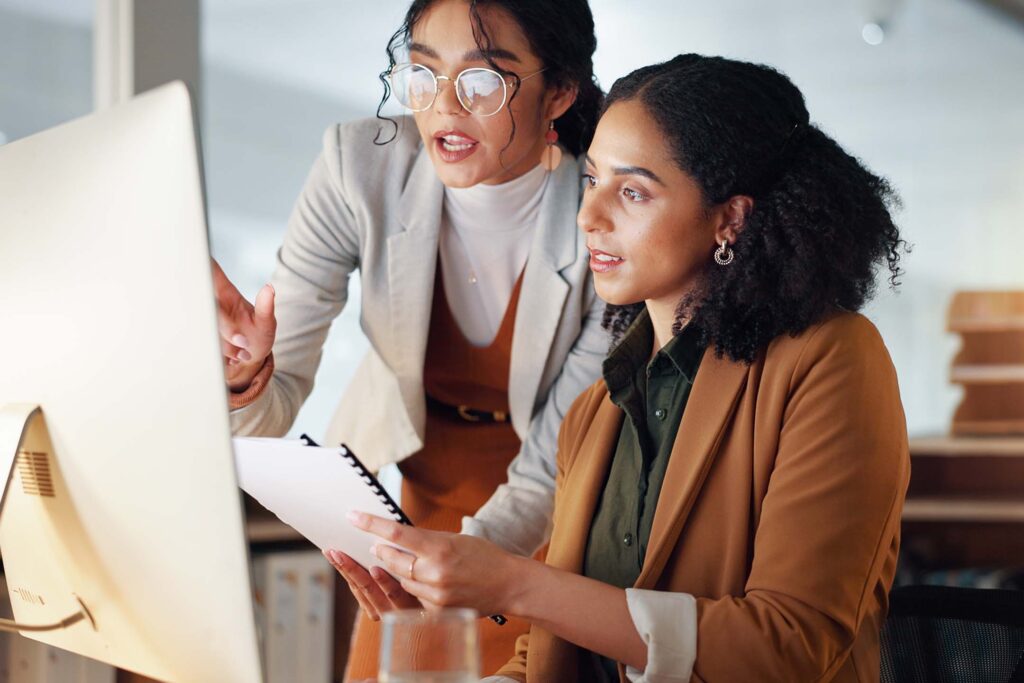 Two office coworkers reviewing information together at a computer. Office Management
