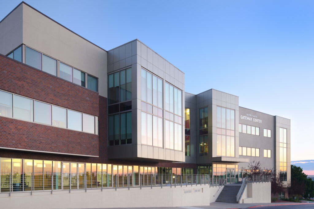 Exterior view of a modern academic building with large windows and signage reading ‘Gateway Center’ at sunset.