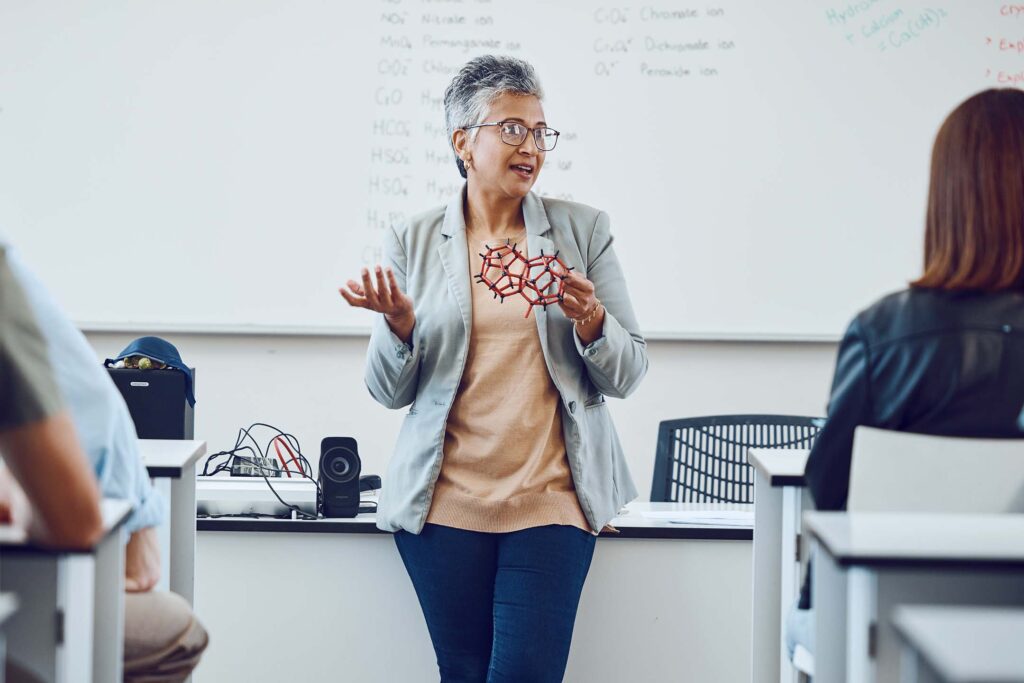 Instructor lecturing at the front of a physics classroom.