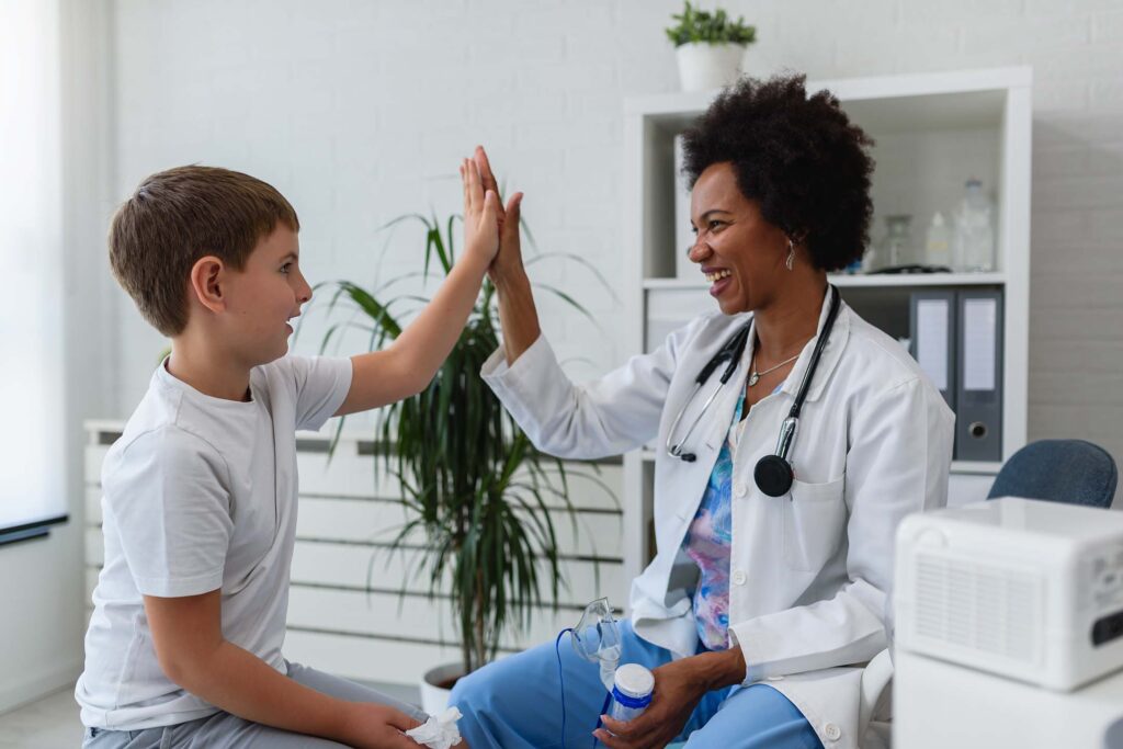 Doctor or healthcare provider high-fiving a child during an exam room visit. Medicine