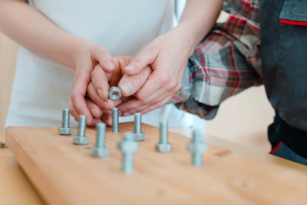 Close-up of hands practicing fine motor tasks with pegs on a therapy board. Occupational therapy