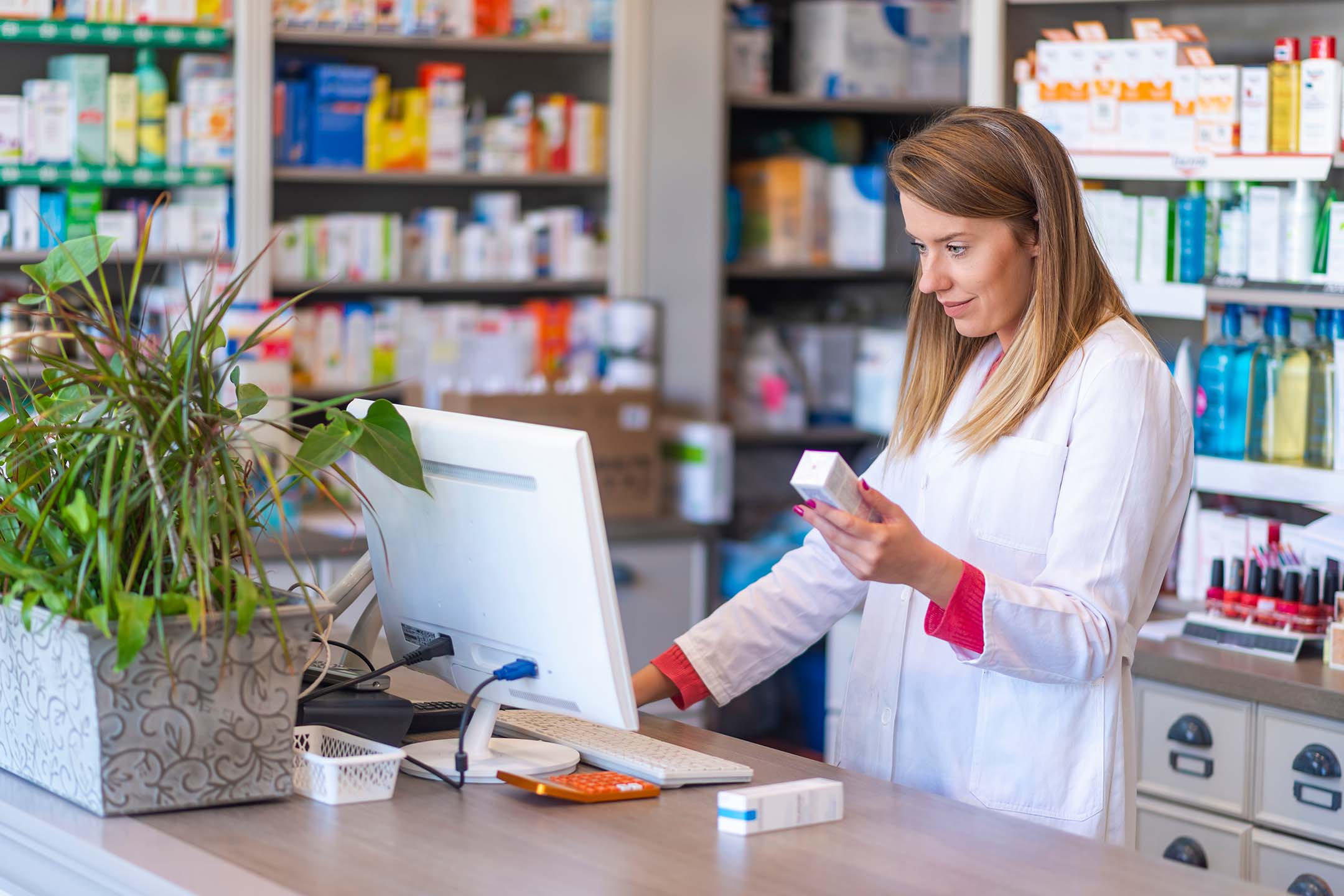 Pharmacist or pharmacy student working at a computer in a pharmacy.
