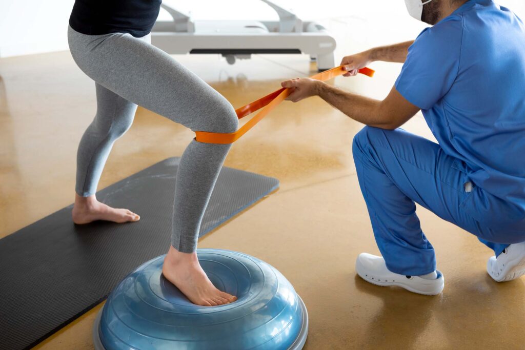 Therapist supporting a patient balancing on a half exercise ball. Physical therapy