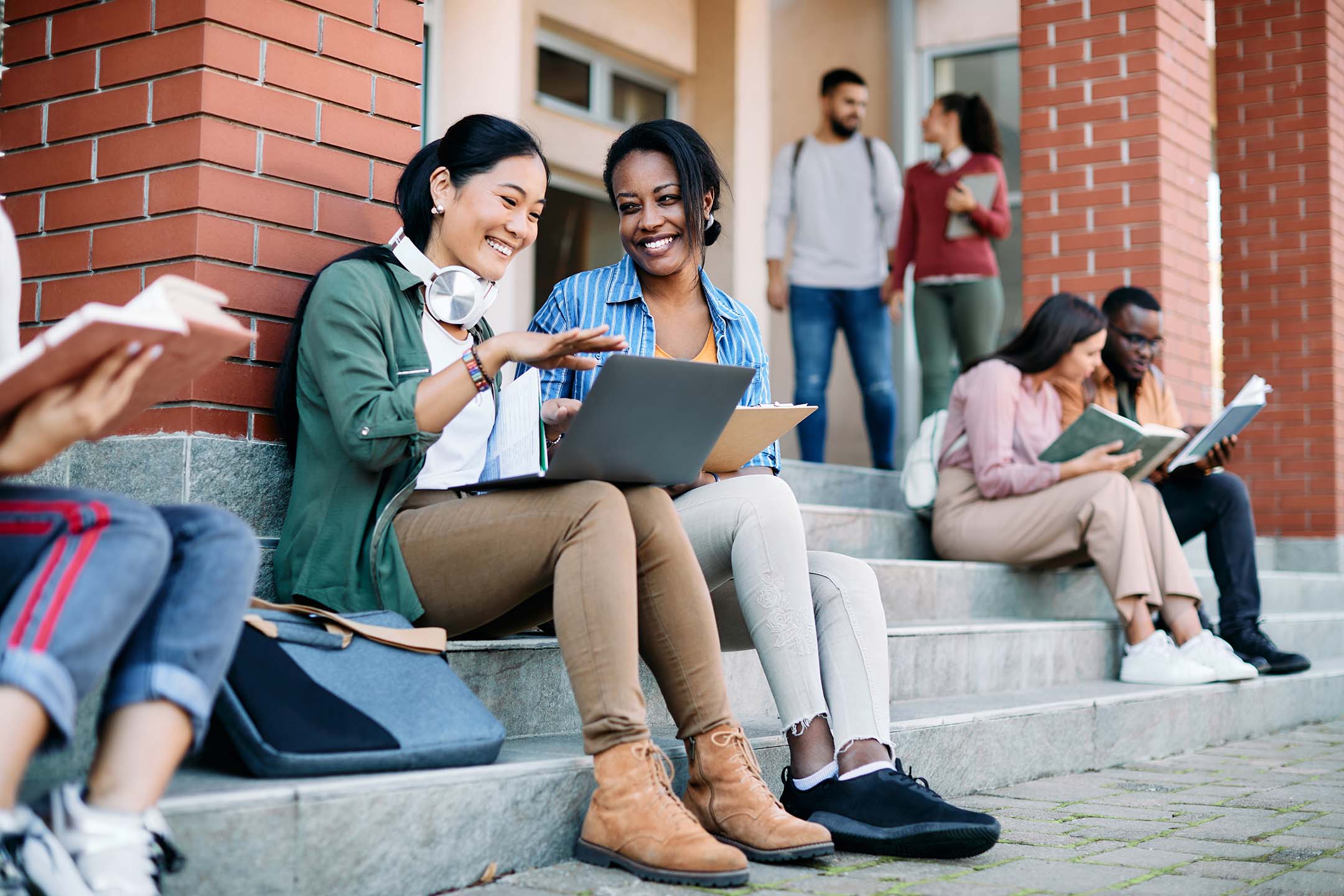 College students sitting outside a campus building and studying together.