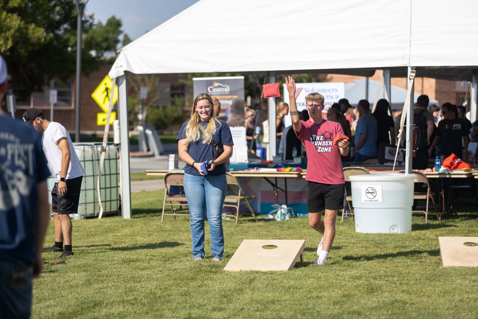 Casper College students laughing and talking while sitting together outdoors at a picnic table during the Welcome Back BBQ.