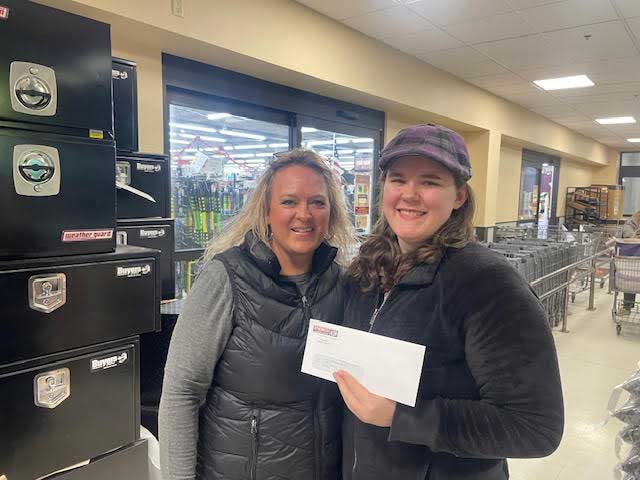 an instructor and student smile while the student holds up an envelope