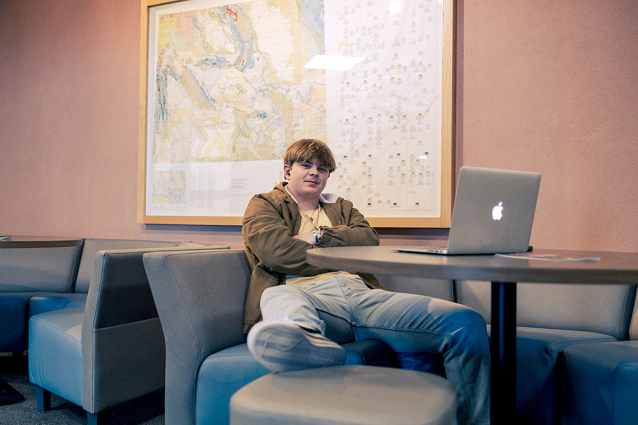 Casper College student studying with a laptop under a large geological wall map in the Wold Physical Science Center.