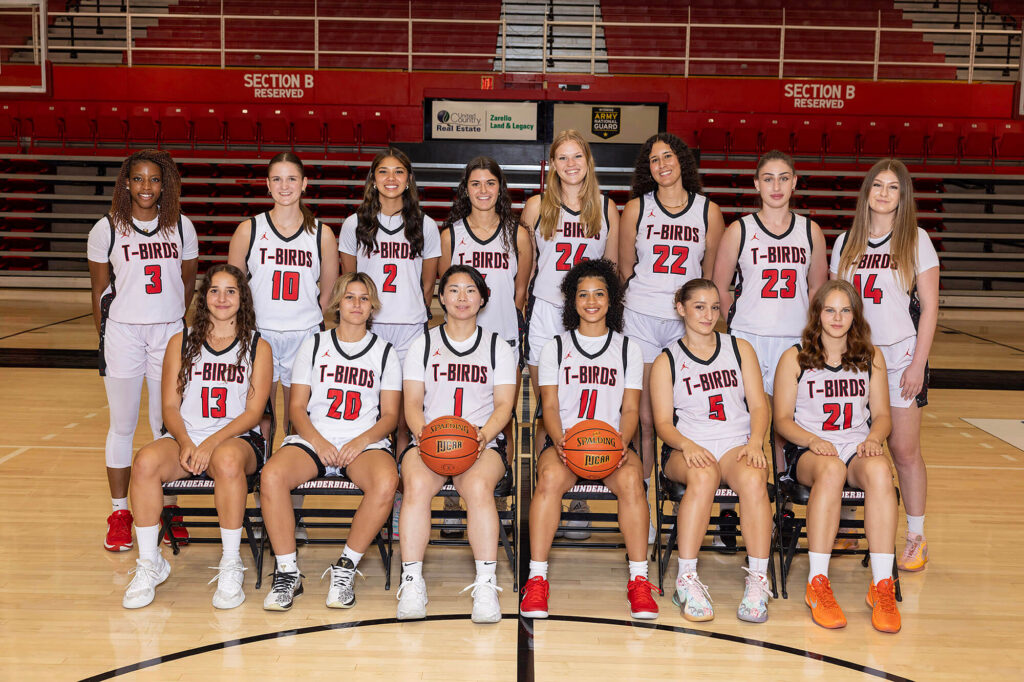 2025-2026 Casper College Lady T-Birds women's basketball team posing for a group photo in their white uniforms on the court.