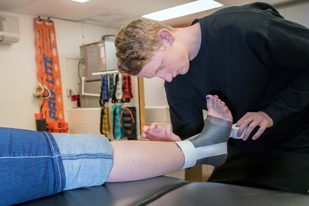 Athletic training student practices ankle taping techniques during a hands-on laboratory session.
