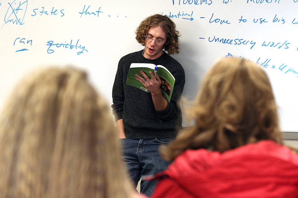 An English student reads aloud from a textbook during a classroom discussion.