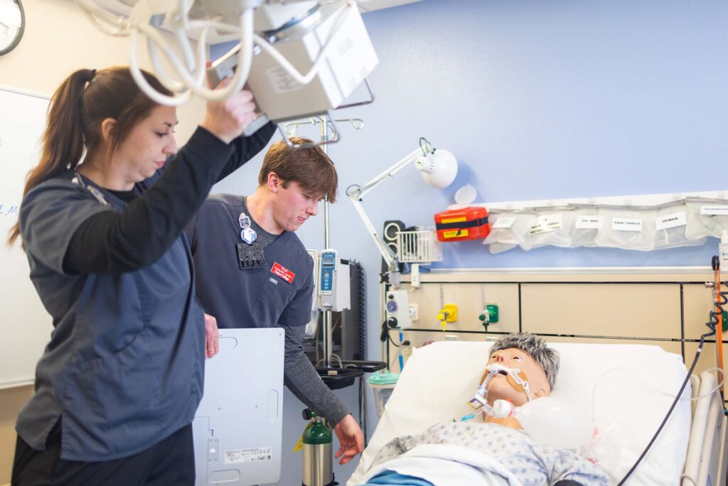 Radiography students prepare a patient simulator for diagnostic imaging in a simulation lab.