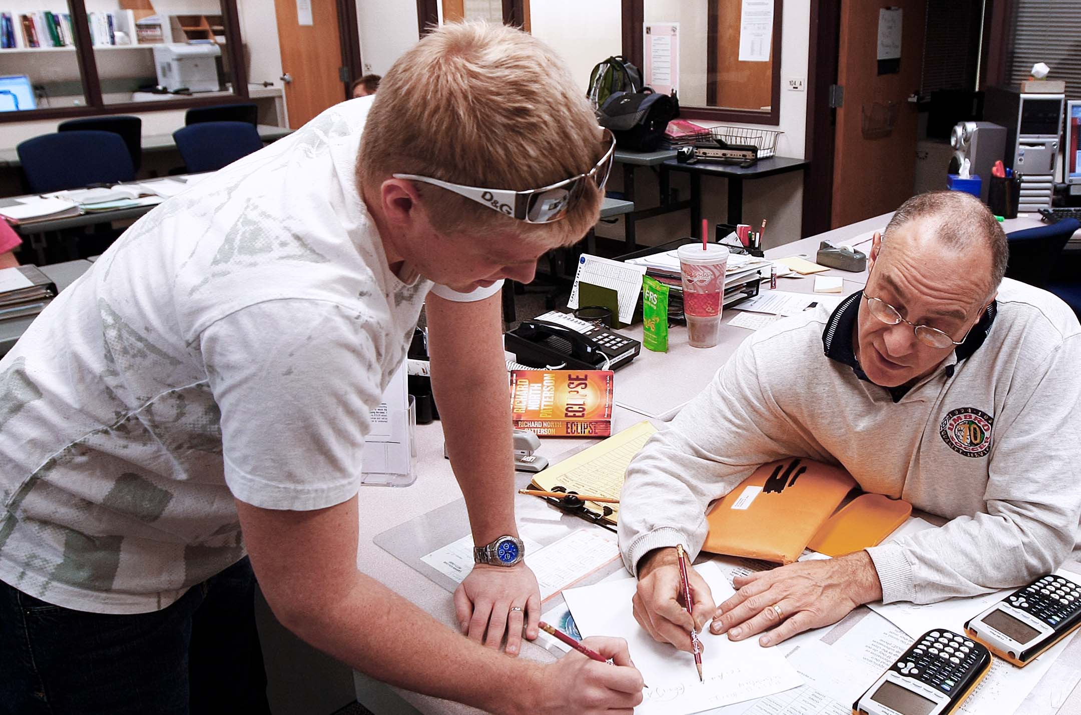 Student receives one-on-one assistance from an instructor while working through math problems.