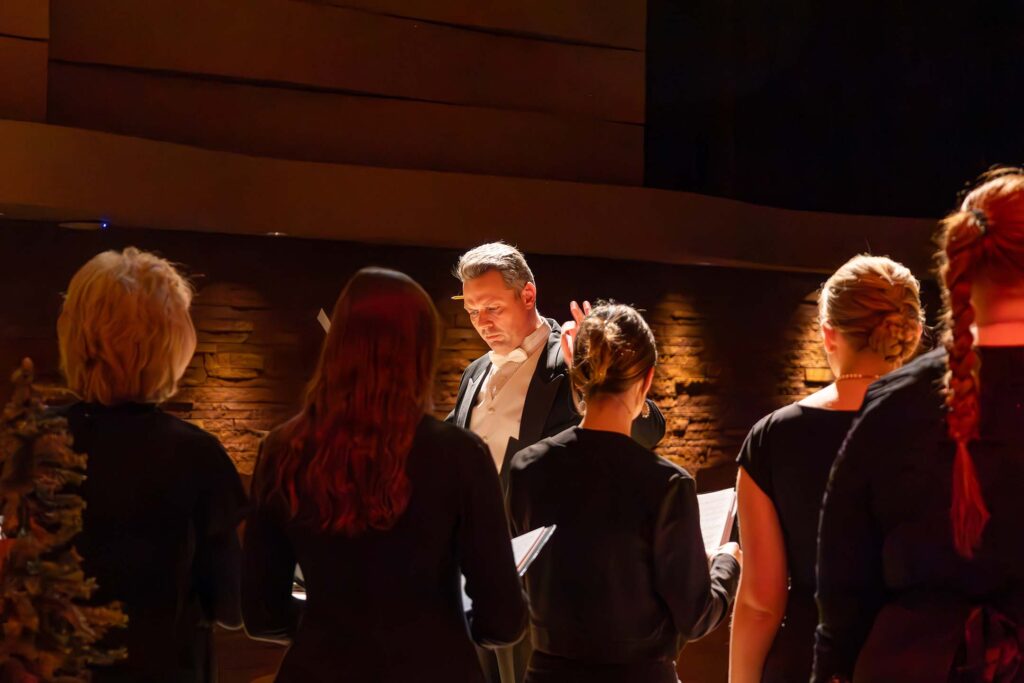 A choir conductor leads student singers during a live concert performance.