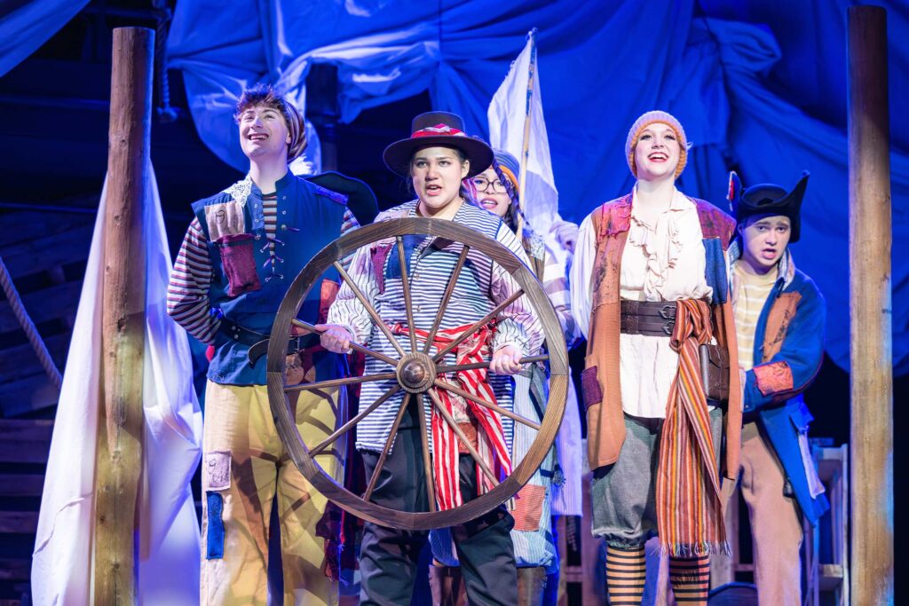 Musical theatre students perform aboard a pirate ship set during a stage production.