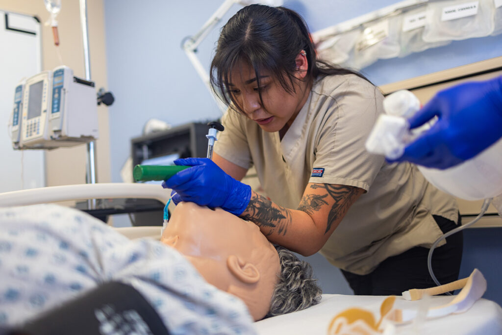 Respiratory therapy student performs endotracheal intubation on a high-fidelity patient simulator during a simulation exercise.