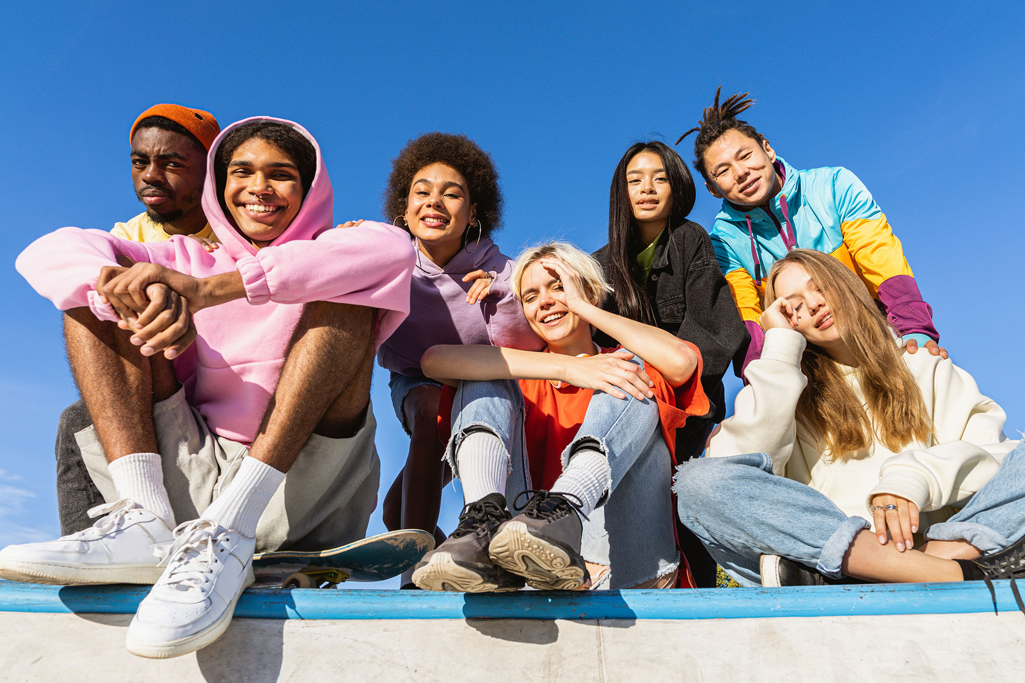 Group of seven diverse young students smiling outdoors on a railing during National GEAR UP Week.