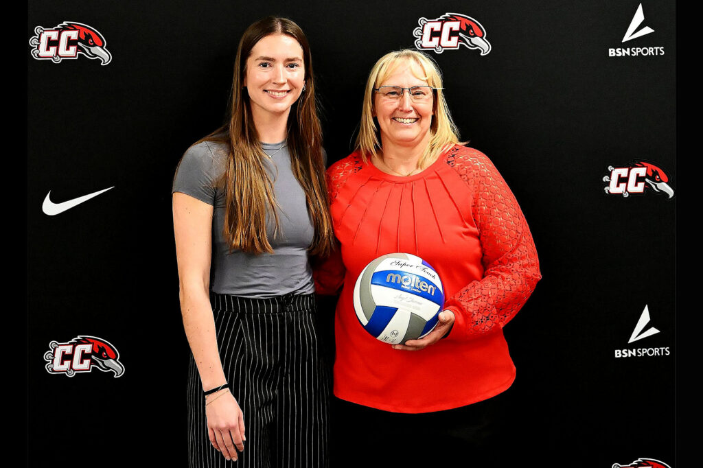 Kelly Wiedemann and Angel Sharman hold a commemorative volleyball celebrating Angel Sharman career wins milestone.