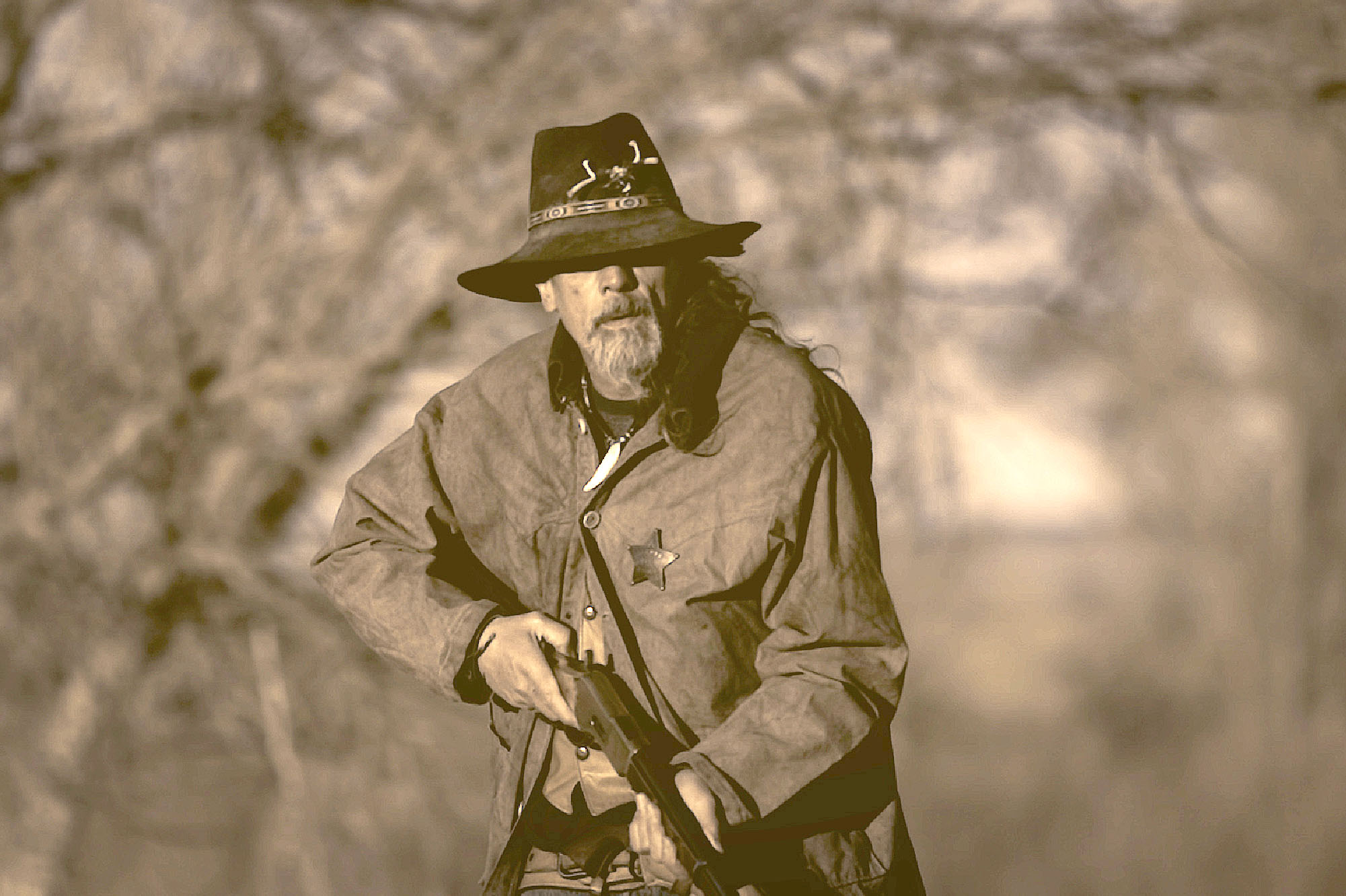 Bearded frontiersman in wide-brimmed hat holding rifle from the HOLE IN THE WALL documentary.