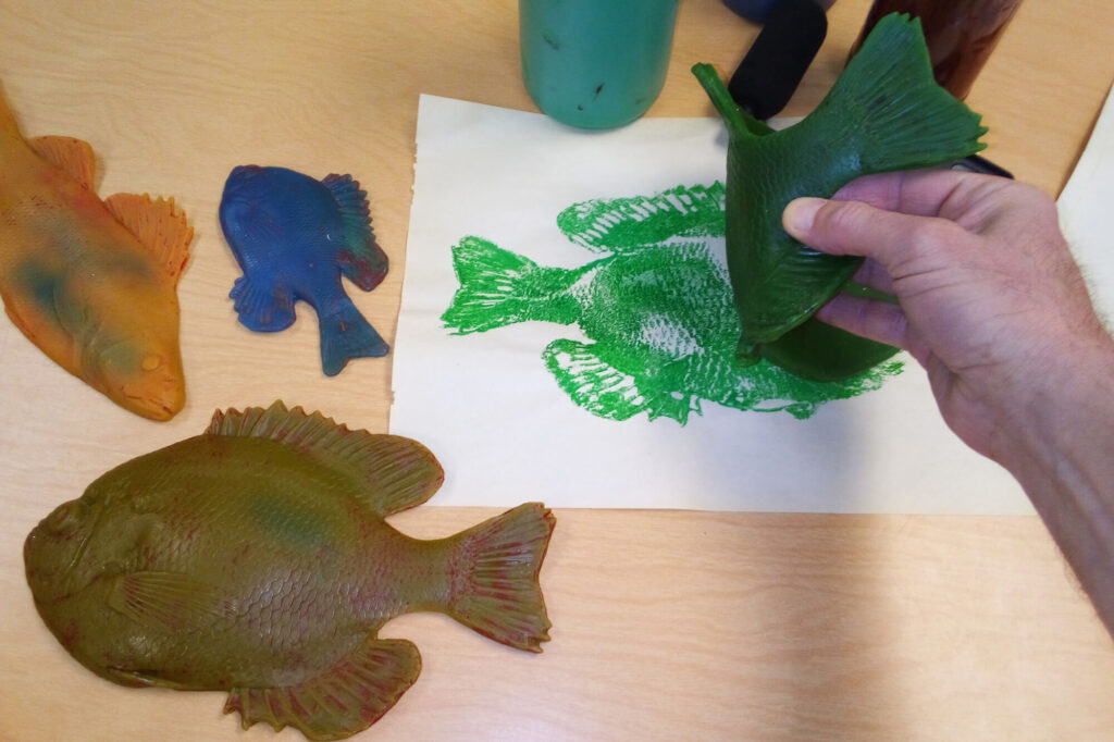 Tate Saturday Club gyotaku fish printing demonstration with colorful rubber fish molds and green ink print on paper